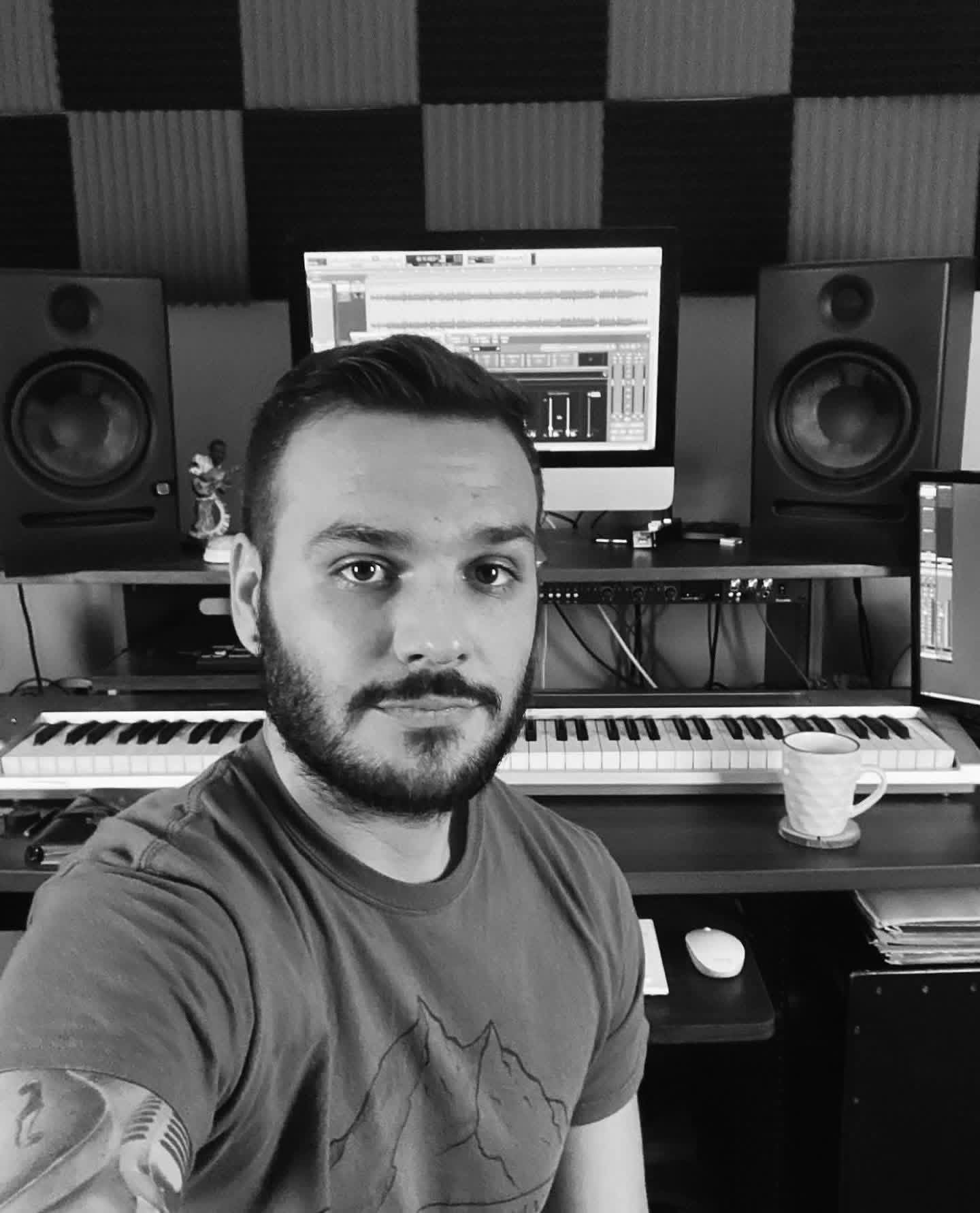 Kagan Williams in his studio, seated in front of studio monitors and a MIDI keyboard