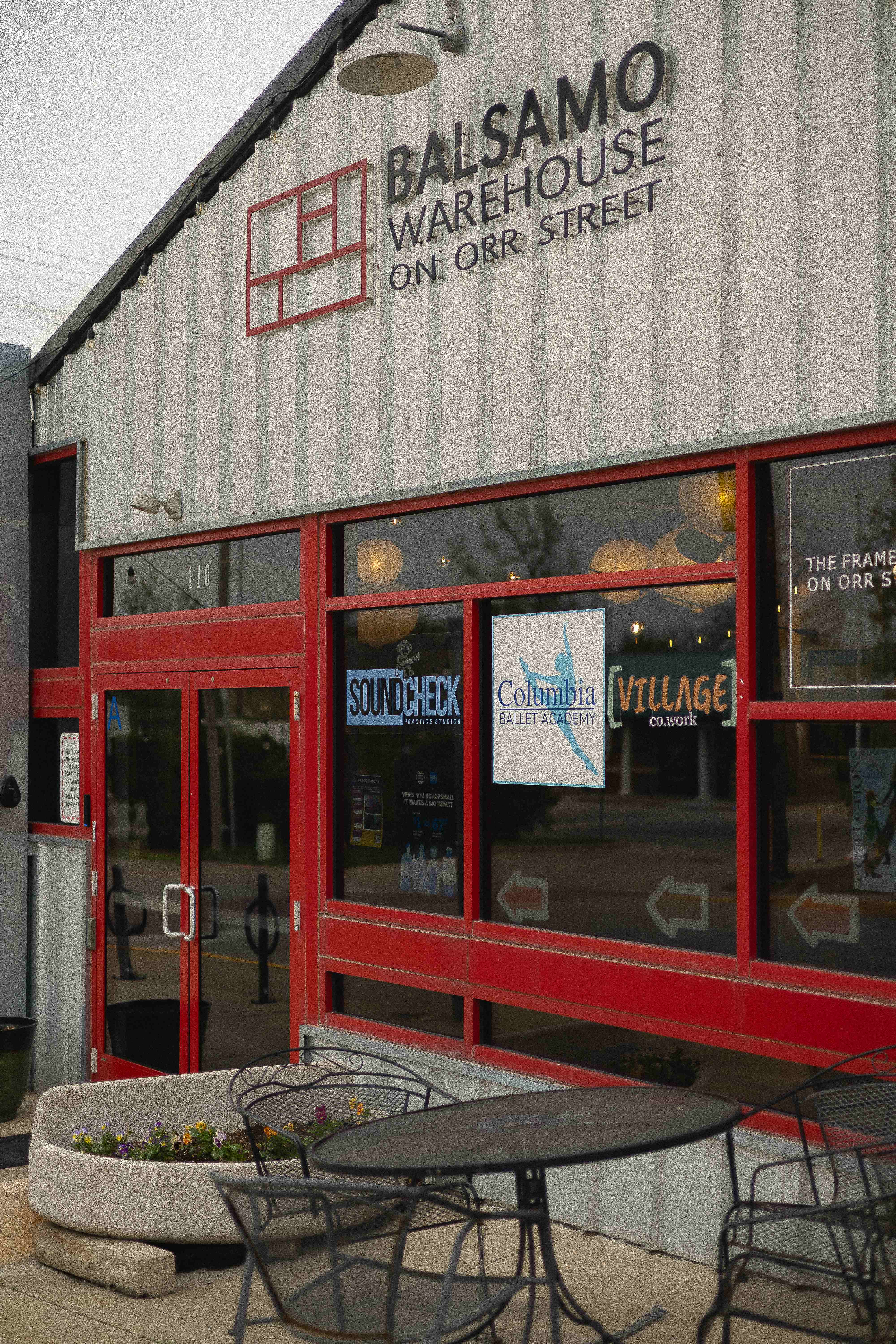 The exterior of the Balsamo Warehouse at 110 Orr Street, with signage for Soundcheck, Columbia Ballet Academy, and Villageco.work